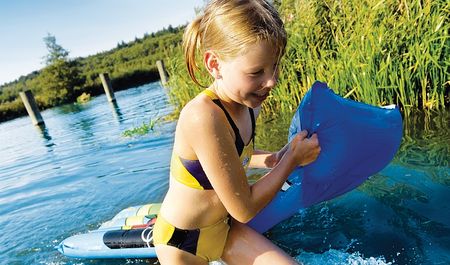 Kleines Mädchen mit Luftmatratze in der Hand lacht und kommt aus dem Wasser, Foto: TMV/Ehn