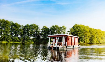 Familie auf fahrendem Bungalowboot, grüne Bäume im Hintergrund, Müritzarm bei Priborn, Mecklenburgische Seenplatte, Foto: TMV/Kirchgessner