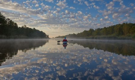 Kanufahrer auf der Peene in der Dämmerung, Wolken spiegeln sich im Wasser, Wälder säumen den Fluss auf beiden Seiten, Stille, Foto: TVV/T. Grundner